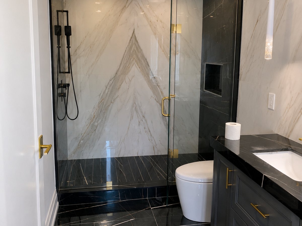 Bathroom with black marble-look walls and a dark blue vanity with brass hardware