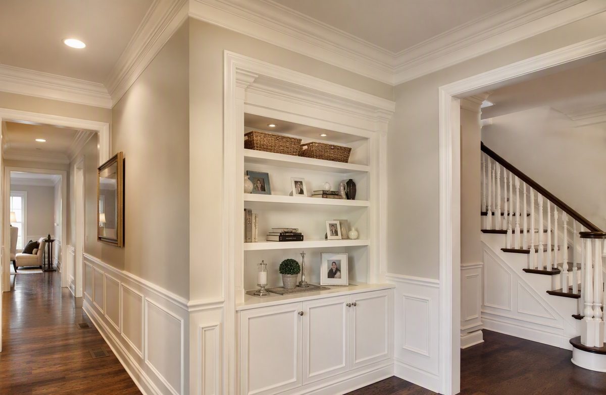 Built-in shelving, wainscoting, and crown moulding in a finished hallway